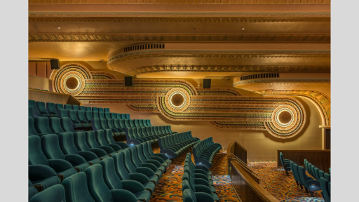 Side view of green art deco cinema seats, with circular patterns on the far wall.