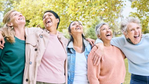 Five older women lined up in a park laughing