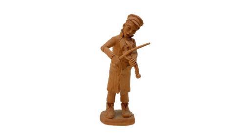 Unpainted, clay sculpture of a man standing and playing a violin. He is wearing a long coat, big, unlaced boots and a cap. His mouth is slightly open, and his head is titled down, supporting the violin as he plays.
