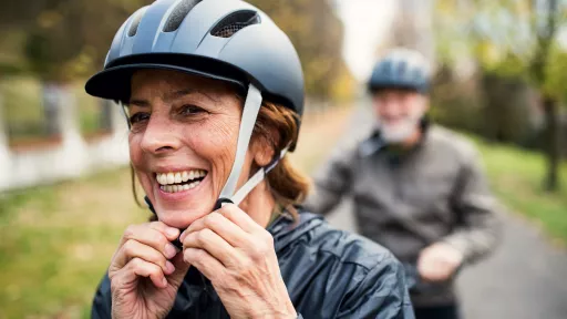 A smiling woman clips on her bike helmet 