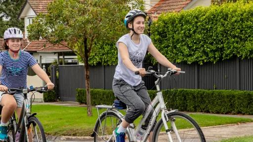 Two people riding bikes on a suburban street