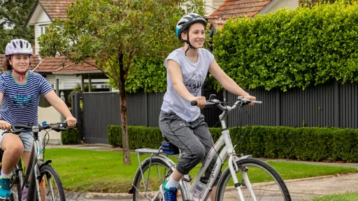 Two people riding bikes on a suburban street