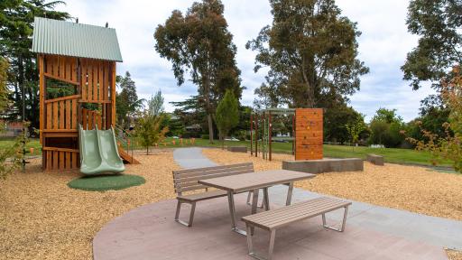 Picnic seating in playground with timber combination play unit in background