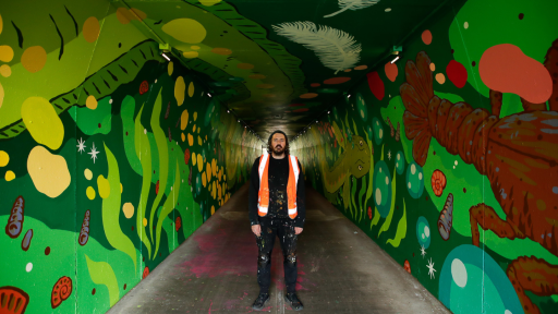 Person standing in the middle of an underpass painted with river creatures