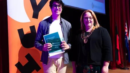 Two people standing, one is holding a certificate