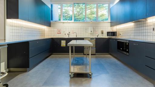 A kitchen space with benches, microwave, and centre island. 