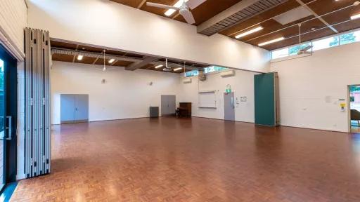 A large empty room with wooden floors and retractable wall panels on either side of the space