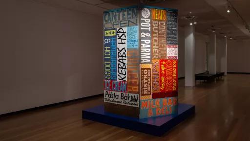 A colorful sign on a wall lists various food items