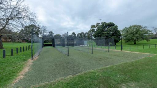 4 cricket net lanes surrounded by green grass and trees