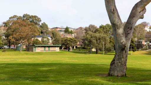 A view across a green sportsfield looking towards a brick building. 