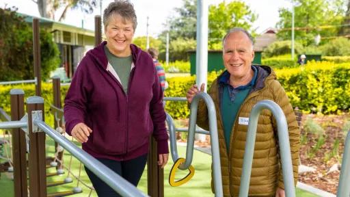 An older man and woman standing with exercise equipment