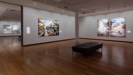 Photograph of large landscape paintings hanging in a gallery