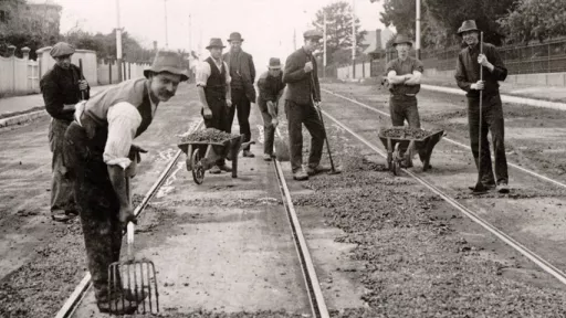 Historical black and white photo of workers with wheelbarrows and pitchforks repairing Riversdale Road