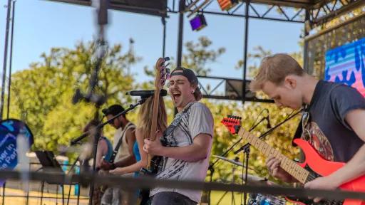 Band performing on stage. The focus is on a person playing guitar.