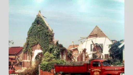 A partially demolished old church with ivy-covered walls. The building's structure is visibly deteriorated with exposed wooden beams and bricks. A red truck labeled 'N.D. Marshall' is parked in front, surrounded by rubble.