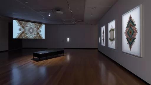 Photo of moving image artwork and photographs in a gallery.