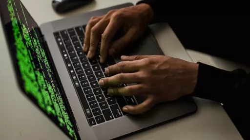 A persons hands typing on a laptop