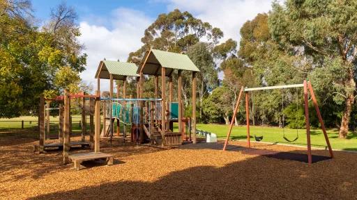 a playground with swings and shaded climbing area