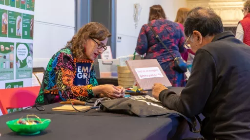 Man sitting across from a woman mending his trousers