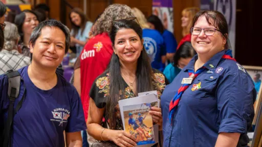 Four people including one in a blue scout uniform smile at camera