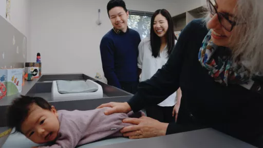 Nurse holds baby with parents in background