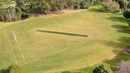 Aerial view of a rectangular sportsground with a cricket pitch in the center