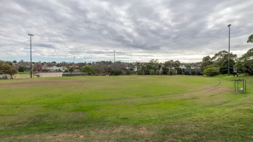 A circular sportsground. Sheltered seating can be seen to the right of the oval. 