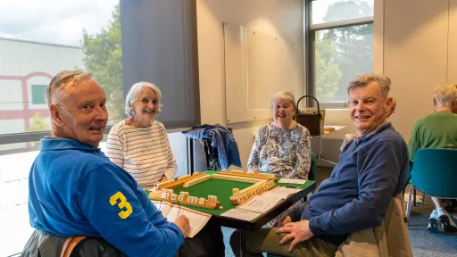 Four people play a board game around a table at the Camberwell Community Centre.