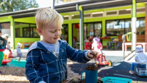 Young child playing with mud at a kindergarten outdoor area