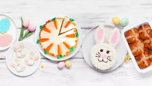 A table covered in Easter treats like bunny cake, hot cross buns and coloured eggs