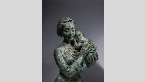 A bronze sculpture of a woman tenderly holding a baby.
