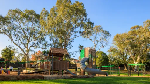 plaground against a backdrop of gum trees. the playground has slides, climbing frames, swings, ladders and ramps
