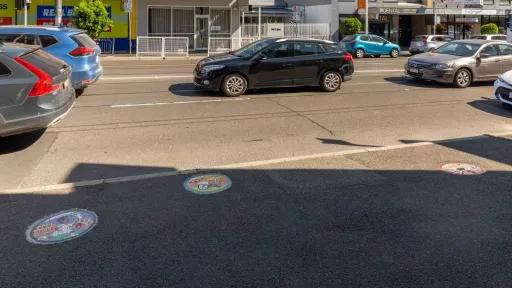 A footpath in shadow with 3 round, tiled mosaics embedded in it