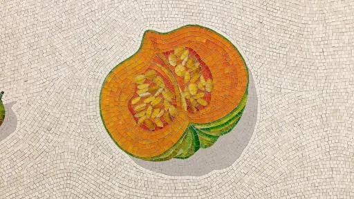 A close up photograph of a mosaic of a pumpkin on a white background
