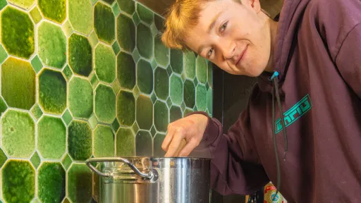 Teenager stands stirring pot on induction stove