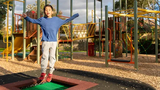 Child bounces on trampoline at playground