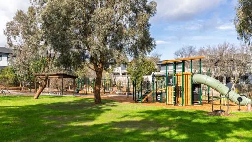 A playground surrounded by trees and green lawn
