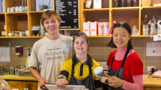 3 young people behind the counter of a cafe 