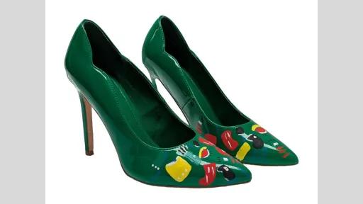 A pair of closed-toe green high heels painted with colourful graphic shapes in red, yellow, blue, green and white.