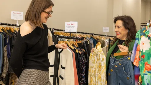 2 people looking through a rack of clothing