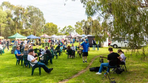 a large grassy area with scattered chairs and market stalls.