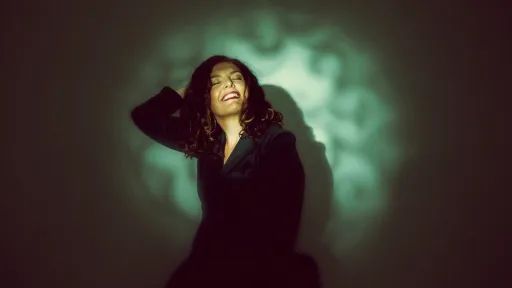 A woman in a black dress posing in front of an illuminated background