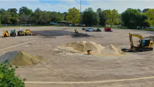 Aerial photo shows sportsground with sandy surface and digging machines