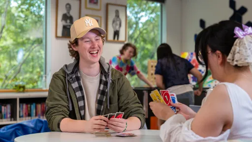Two teenagers laughing as they play Uno card game