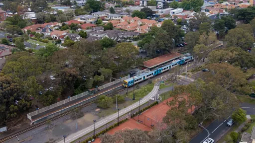 Aerial photo shows train at station platform with residential streets in background