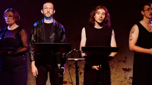 6 people behind microphones looking at the camera