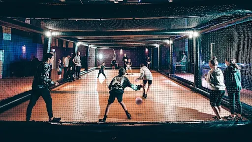 Helmeted players on an indoor court playing dodgeball