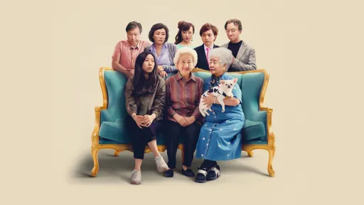 A group photo with one young woman and two old women sitting on a long armchair with blue cushions and gold frame. The old woman on the right is carrying a small black and white dog. Behind the chair stands three men and two women. 