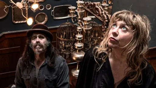 Photo of a man and a woman standing on a staircase surrounded by silver platters on the wall.