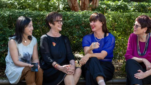 Four middle-aged women sitting outside and chatting